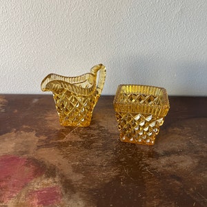 May include: A set of two amber glass sugar and creamer containers with a diamond pattern.
