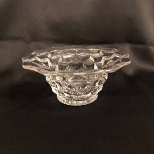May include: A clear glass bowl with a scalloped rim and a textured, diamond-shaped pattern. The bowl is empty and sits on a black surface.
