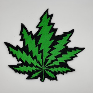 May include: Green and black embroidered patch of a marijuana leaf with a lightning bolt design.