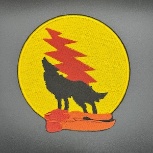 May include: A yellow circular patch with a black wolf howling at a red lightning bolt. The wolf is standing on a red and orange ribbon.