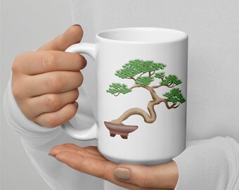 May include: White ceramic mug with a green bonsai tree illustration. The bonsai tree has a brown trunk and is in a brown pot.