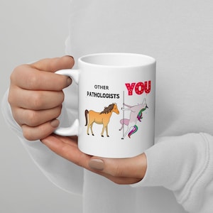 Könnte beinhalten: Eine weiße Keramiktasse mit einem schwarzen und roten Design. Der Text "Other Pathologists" befindet sich auf der linken Seite der Tasse, und der Text "YOU" befindet sich auf der rechten Seite der Tasse. Ein braunes Pferd befindet sich auf der linken Seite der Tasse, und ein rosa Einhorn befindet sich auf der rechten Seite der Tasse.