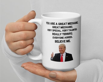 May include: White ceramic mug with a black and white image of a man giving a thumbs up. The text on the mug reads "You are a great mechanic, great mechanic. Very special, very talented. Really terrific. Everyone agrees. Believe me."