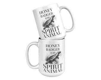 May include: Two white ceramic mugs stacked on top of each other. Both mugs feature a black and white illustration of a honey badger with the text "Honey Badger is my Spirit Animal".