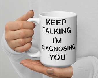 May include: White ceramic mug with black text that reads "Keep Talking I'm Diagnosing You".
