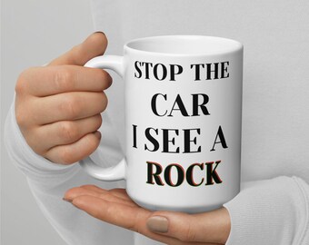 May include: White ceramic coffee mug with black text that reads "Stop the car I see a rock".