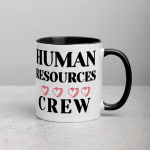 May include: White ceramic mug with a black rim and handle. The mug has black text that reads "HUMAN RESOURCES CREW" with four red hearts between the words.