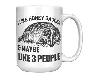 May include: White ceramic mug with a black and white illustration of a honey badger and the text "I like honey badger & maybe like 3 people".