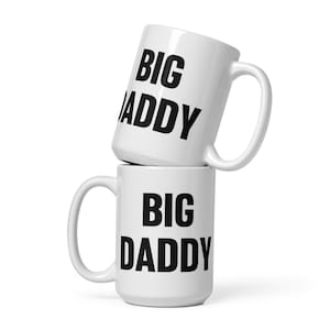 Puede incluir: Dos tazas de cerámica blanca apiladas una encima de la otra. La taza de arriba dice "BIG DADDY" en texto negro. La taza de abajo dice "BIG DADDY" en texto negro.