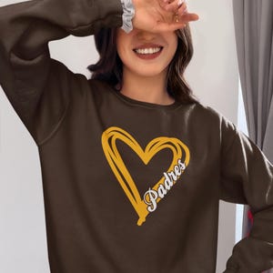 May include: Brown sweatshirt with a yellow heart and the word "Padres" inside the heart.