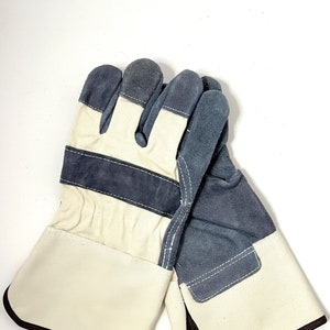 May include: A pair of work gloves with a white canvas and gray suede palm. The gloves have a brown cuff and a reinforced thumb.