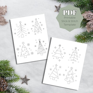 May include: Two white cards featuring black line drawings of Christmas trees and stars. The cards are labelled "PDF Printable Stick & Stitch Template". The cards are surrounded by festive decorations.