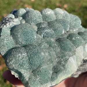 May include: A raw mineral specimen featuring a cluster of rounded, botryoidal formations in shades of translucent teal and seafoam green. The surface displays a crystalline, textured appearance with visible radiating patterns along the edges.