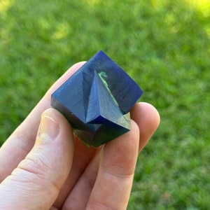 May include: A blue and green resin cube with a geometric design. The cube is made of clear resin with blue and green swirls.