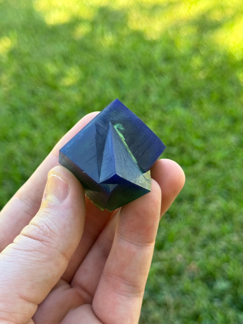 May include: A blue and green resin cube with a geometric design. The cube is made of clear resin with blue and green swirls.