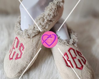 May include: Pair of beige knitted slipper socks with a fluffy white lining. The socks have a pink monogram "KES" embroidered on the front.