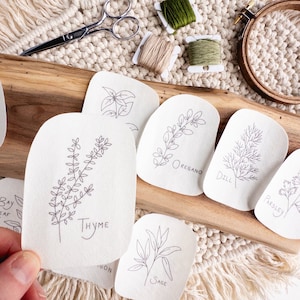 May include: A set of embroidery patterns featuring various herbs, including bay leaf, thyme, oregano, dill, parsley, and sage. The patterns are printed on white fabric and are ready to be stitched.