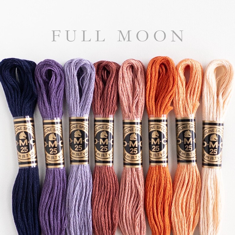 Eight skeins of DMC Mouliné Special embroidery thread in assorted colors: dark blue, medium purple, light purple, dark mauve, light mauve, bright orange, light orange, peach. Each skein is labeled with DMC branding and specifications. The text 'FULL MOON' is displayed above the threads.