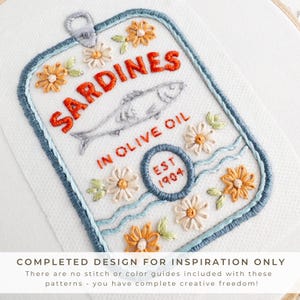 Close-up image of a completed stick and stitch embroidery pattern depicting a sardine tin labeled “Sardines in Olive Oil” with “EST 1904” and decorative floral details. The design is stitched in red, orange, blue, and pastel tones. A banner at the bottom reads: “COMPLETED DESIGN FOR INSPIRATION ONLY – There are no stitch or color guides included with these patterns – you have complete creative freedom!”
