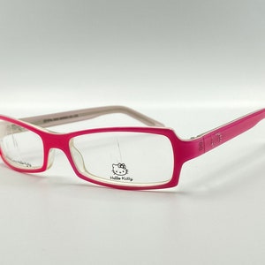May include: Pink and white plastic framed glasses with clear lenses. The Hello Kitty logo is printed on the right lens.
