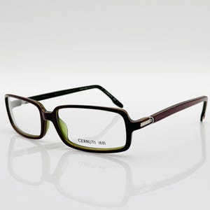 May include: Brown and green rectangular eyeglasses with clear lenses. The frame has a silver accent on the side and the text "CERRUTI 1881" is printed on the right lens.