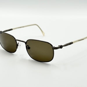 May include: A pair of brown metal sunglasses with brown lenses. The sunglasses have a simple, classic design.