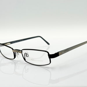 May include: Black metal frame eyeglasses with clear lenses. The brand name "Blumarine" is printed on the right temple.