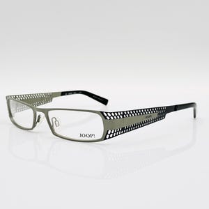 Puede incluir: Gafas de metal de color plateado y negro con el logotipo de Joop! en la patilla derecha.