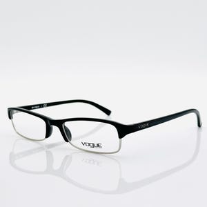 May include: Black rectangular eyeglasses with a silver-tone lower rim. The glasses have a sleek, modern design with the brand name "VOQUE" on the temple. The frames are set against a white background.