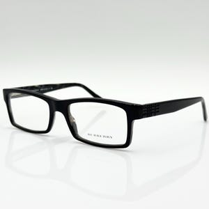 May include: Black rectangular eyeglasses with clear lenses. The frames have a matte finish and feature the brand name "BURBERRY" on the right lens. The temples have a textured design.