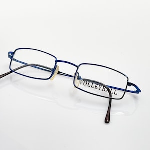 May include: Blue metal frame eyeglasses with clear lenses. The right lens has the word "VOLLEYBALL" printed on it.