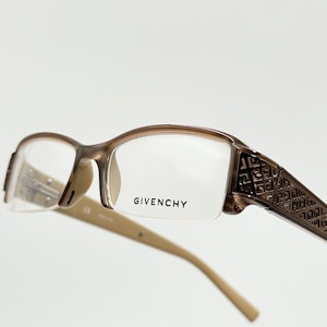 Op de afbeelding: Bruine en beigekleurige bril met een geometrisch patroon op de pootjes. De merknaam "GIVENCHY" staat op de rechterlens gedrukt.