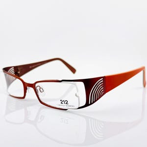May include: Rectangular eyeglasses with a gradient frame, transitioning from brown to orange. The glasses feature a cut-out design on the temples and the text "212" on the frame. The lenses are clear.