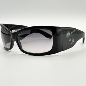 May include: Black sunglasses with a rectangular frame and dark gray lenses. The sunglasses have a logo on the side.