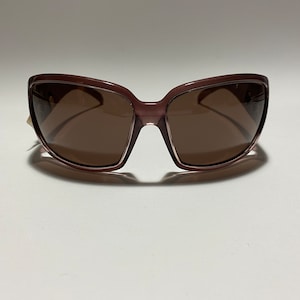 May include: A pair of brown sunglasses with a rectangular frame. The sunglasses have brown lenses.