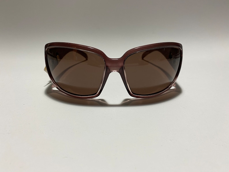 May include: A pair of brown sunglasses with a rectangular frame. The sunglasses have brown lenses.