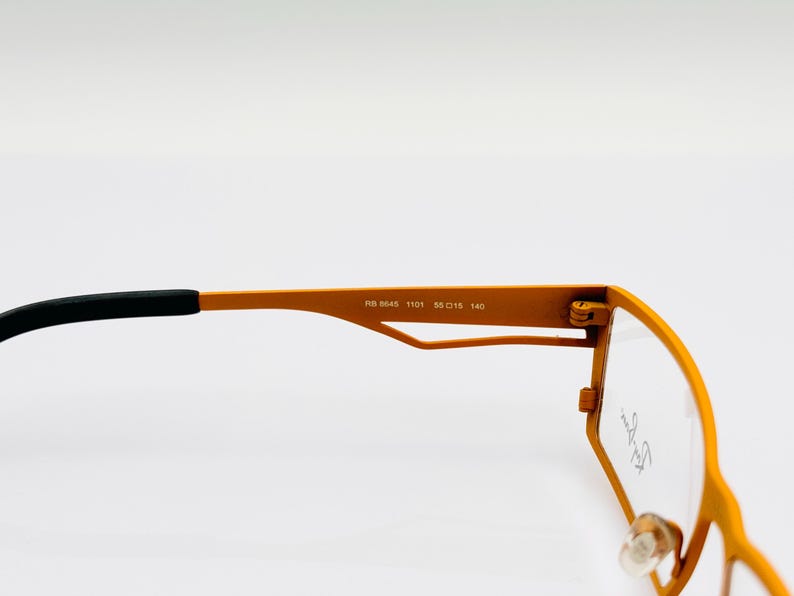 K&ouml;nnte beinhalten: Orangefarbene Metallgestellbrille mit schwarzen B&uuml;geln. Der Rahmen tr&auml;gt den Text "RB 5045 1101 55 015 140", der auf der Innenseite des Rahmens aufgedruckt ist.