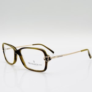 Puede incluir: Gafas de vista rectangulares de color verde y dorado con el texto "TRUSSARDI EYES" en la patilla derecha.