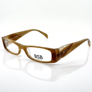 May include: Brown rectangular eyeglasses with a subtle gradient effect. The frames feature a rounded rectangular shape with the text "BSB -EYES-" on the lens. The temples have a curved design and a signature logo.