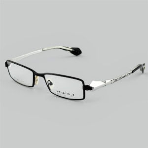 Könnte beinhalten: Schwarze rechteckige Brille mit silbernen und weißen Akzenten. Die Bügel weisen ein geometrisches Muster auf, und der Markenname "KOALI" ist auf dem Rahmen zu sehen. Die Brille hat ein modernes, stilvolles Design.