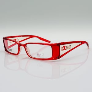 Peut inclure: Lunettes de vue en plastique rouge avec des verres transparents. Le nom de la marque "EXALT CYCLE" est imprimé sur la branche droite.