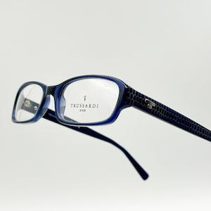 Puede incluir: Gafas azules con montura texturizada y el nombre de la marca "TRUSSARDI EYES" impreso en la lente derecha.