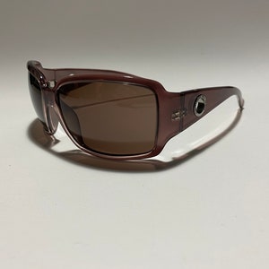 May include: A pair of brown plastic sunglasses with brown lenses. The sunglasses have a silver metal accent on the side.