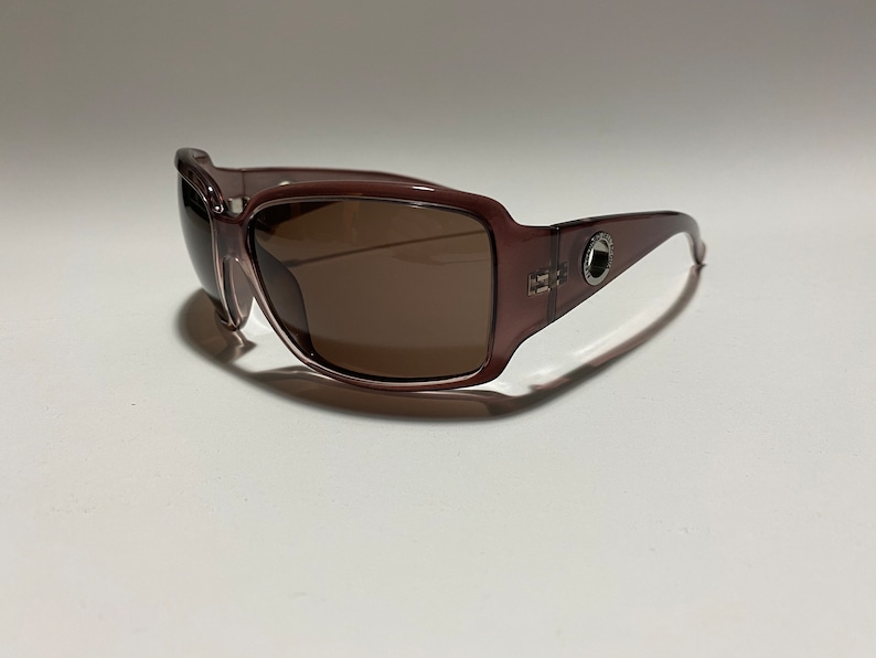 May include: A pair of brown plastic sunglasses with brown lenses. The sunglasses have a silver metal accent on the side.