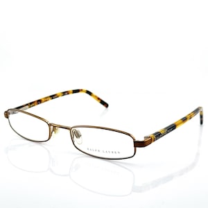 May include: Rectangular eyeglasses with a thin, bronze-coloured metal frame. The temples feature a tortoiseshell pattern. The brand name "RALPH LAUREN" is printed on the right lens. The glasses are set against a white background.