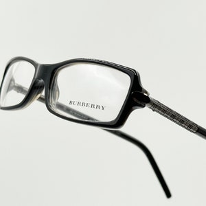 Puede incluir: Gafas rectangulares negras con el logotipo de Burberry en la montura.