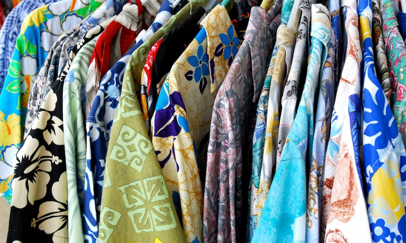 vintage '90s Hawaiian shirts displayed. Each shirt features different patterns such as lush landscapes, exotic flowers, and classic beach scenes, embodying a retro and relaxed vibe perfect for vacations or as a unique gift