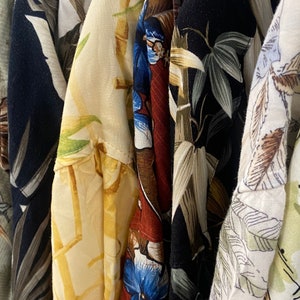 vintage '90s Hawaiian shirts displayed. Each shirt features different patterns such as lush landscapes, exotic flowers, and classic beach scenes, embodying a retro and relaxed vibe perfect for vacations or as a unique gift