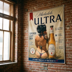 May include: A rectangular wall banner featuring a Michelob ULTRA advertisement. The design includes a beer bottle, text detailing 2.6 carbs and 95 calories, and a graphic of a person in a bikini. The text reads It's Only Worth It If You Enjoy It.