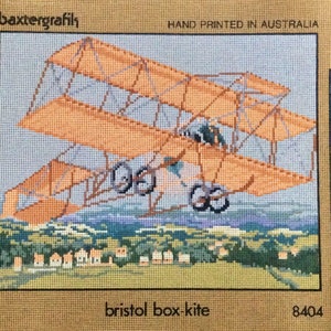 May include: A cross-stitch pattern of a vintage Bristol box-kite airplane flying over a field of houses. The pattern is hand-printed in Australia and includes a color chart for the embroidery.
